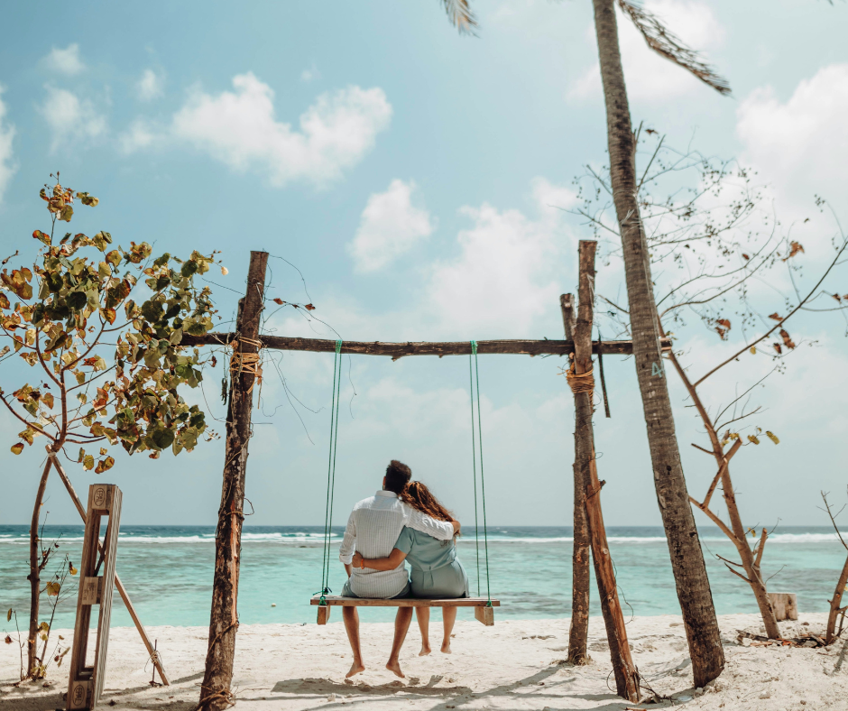 Pareja de novios disfrutando de una luna de miel a medida en una playa paradisíaca
